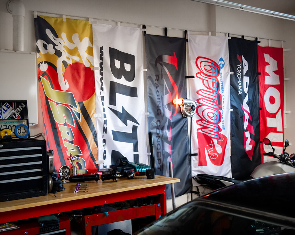 Transform your garage with our Nobori Flags! Motul, Option2, Advan, Varis, Blitz, and J's are featured on this wall.